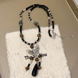 Detail of beaded necklace with silver butterfly charm and black teardrop pendant