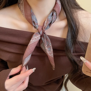 Detail of a brown paisley silk scarf necklace tied elegantly around a woman's neck
