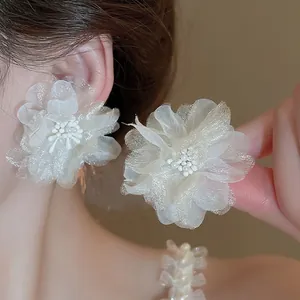 Elegant cream white tulle flower stud earrings with pearl centers worn by model
