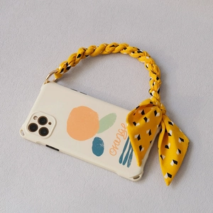 Detail of cream phone case with orange illustration and yellow braided bow strap