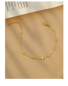 Detailed view of a gold-plated star pendant bracelet with zircon on silk fabric