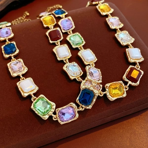 Close-up of vintage square gemstone necklaces in multiple colors on a velvet stand