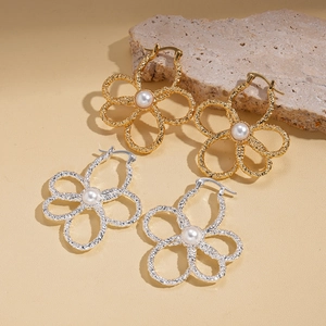 Elegante goldene und silberne Blumenohrringe mit Perlen auf einem Natursteinsockel