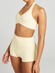 Detail of light yellow halter sports bra and high waist shorts gym set for women