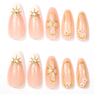 Detailed view of pink almond press-on nails with 3D gold stars and floral relief patterns