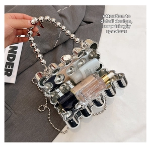 Silver metallic handbag with wave pattern and beaded handle showing interior storage