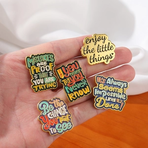 Retro alloy enamel pins set with inspirational quotes on warm wood and silk background