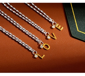 Detail of four S925 silver beaded chains with gold LOVE letter pendants and zircons
