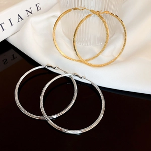 Detailed view of large gold and silver hollow hoop earrings with a textured matte finish