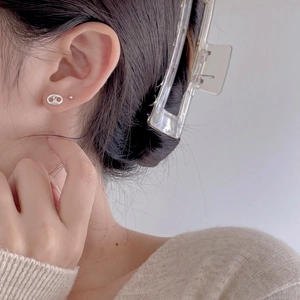 Side view of model wearing silver hollow oval studs and a clear large hair claw clip