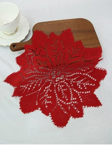 Close-up of red lace knitted round placemat with intricate floral hollow crochet detail