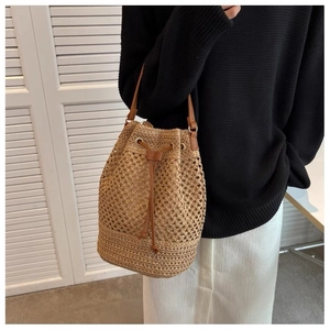 Detail of straw bucket bag featuring brown leather drawstring and adjustable shoulder strap