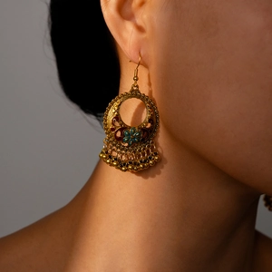 Close-up of vintage gold hollow flower earrings with blue enamel and metallic fringe beads