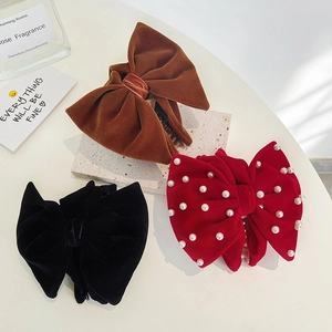 Velvet bow hair claws in black, caramel, and pearl-studded red for elegant hairstyling