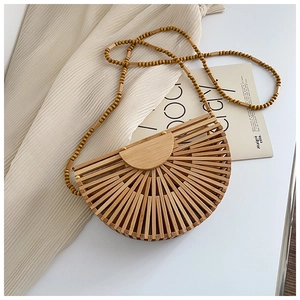 Detail of a semi-circular bamboo woven handbag with beaded strap on a white backdrop