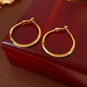 Minimalist twisted gold hoop earrings on red jewelry box with a polished finish