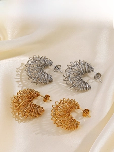 Detail view of gold and silver spring style C-shape hoop earrings on silk fabric
