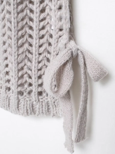 Dettaglio del gilet in maglia grigio chiaro con fiocco laterale e trama del tessuto