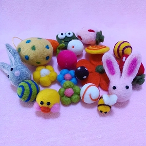 Flat lay of colorful wool felt charms featuring bees, rabbits, ducks and floral shapes