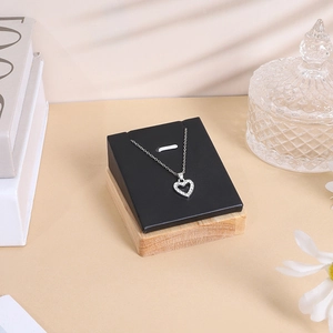 Detail of heart pendant necklace on black velvet stand with a premium wooden base