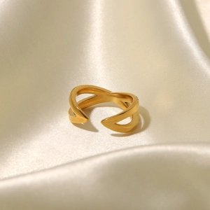 Überkreuzter Ring mit 18K Goldbeschichtung und weißen Diamanten auf beigem Seidenstoff