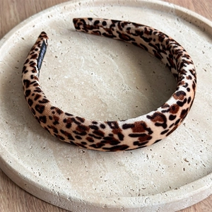 Detail of leopard print velvet headband with wide padded design on a stone tray