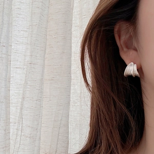 Minimalist brushed silver C-shaped earrings with unique folded texture on female model