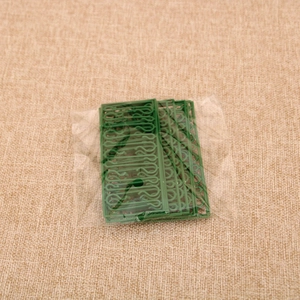 Detail showing green decorative plastic hooks for Christmas ornaments in clear packaging