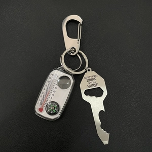 Close-up of metal keychain featuring a survival compass, thermometer, and bottle opener tool