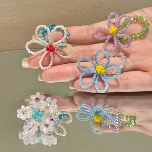 Détail de bagues fleurs faites main avec perles de cristal colorées et reflet sur un miroir