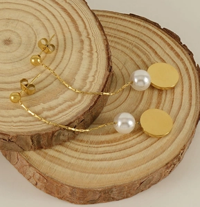 Detail of long gold chain earrings featuring white pearl and round geometric pendant