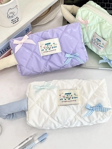 Quilted bow pencil cases in purple mint and white colors on a clean white desk