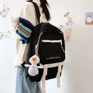 Black and white canvas backpack with a cute white duck keychain and adjustable straps