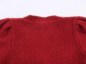 Dettagli dello scollo in maglia rossa e delle spalle a sbuffo sul cardigan