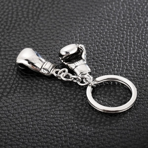 Detailed close-up of shiny stainless steel mini boxing glove keychains on black leather