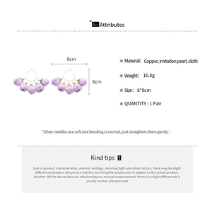 Detailed spec view of purple flower earrings with faux pearls and copper frame