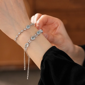 Detail of silver chain bracelet featuring oval blue stones and floral zircon accents