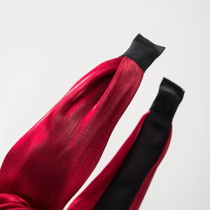 Gros plan d'un serre-tête en satin rouge avec une extrémité en ruban noir pour le confort