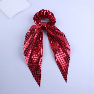Macro shot of red sequin scrunchie with bow tie detail and reflective square pattern