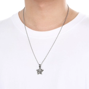 Detail shot of a silver vintage star pendant with moon motifs worn by a male model