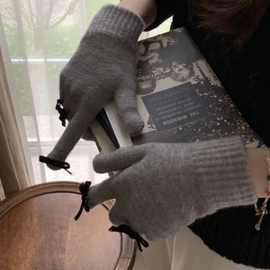 Detail of grey knitted gloves with black bow and touchscreen design for winter warmth