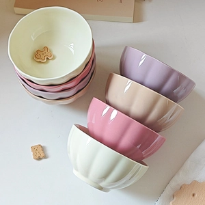 Minimalist ceramic striped rice bowls in assorted pastel colors on a natural wooden table