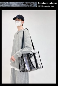 Model wearing a clear PVC tote bag with black trim and adjustable shoulder strap