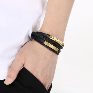 Close-up of men's multi-layer black leather bracelet with gold metal clasp on wrist
