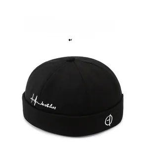 Detailed close-up of a black cotton Miki Hat with white letter embroidery and round icon