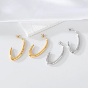Minimalist U-shaped and V-shaped metal earrings in gold and silver on white silk