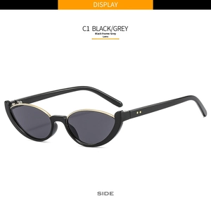 Detail view of black cat-eye sunglasses featuring gold metal trim and grey lenses