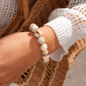 Close-up of geometric acrylic beaded bracelet with natural marble texture on a wrist