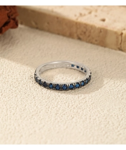 Detail of S925 sterling silver eternity ring with channel-set blue gems on stone texture