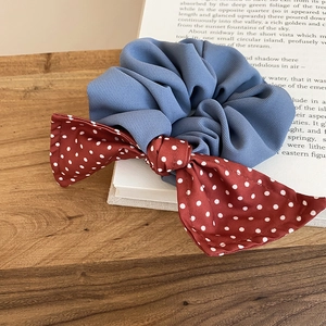 Detailed texture of blue scrunchie with red polka dot bow on a vintage book